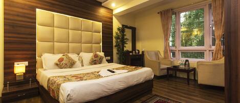 A modern bedroom with a large bed, a ceiling fan, a window with curtains, and a small table with a lamp.