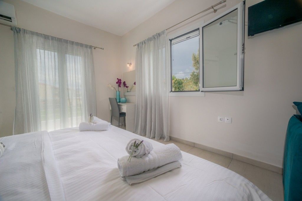 A hotel room with a bed, a desk, and a window.