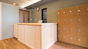 A reception area with a wooden reception desk, a clock on the wall, and a set of lockers to the right.