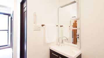 A modern bathroom with a white sink, a large mirror, and a towel rack.