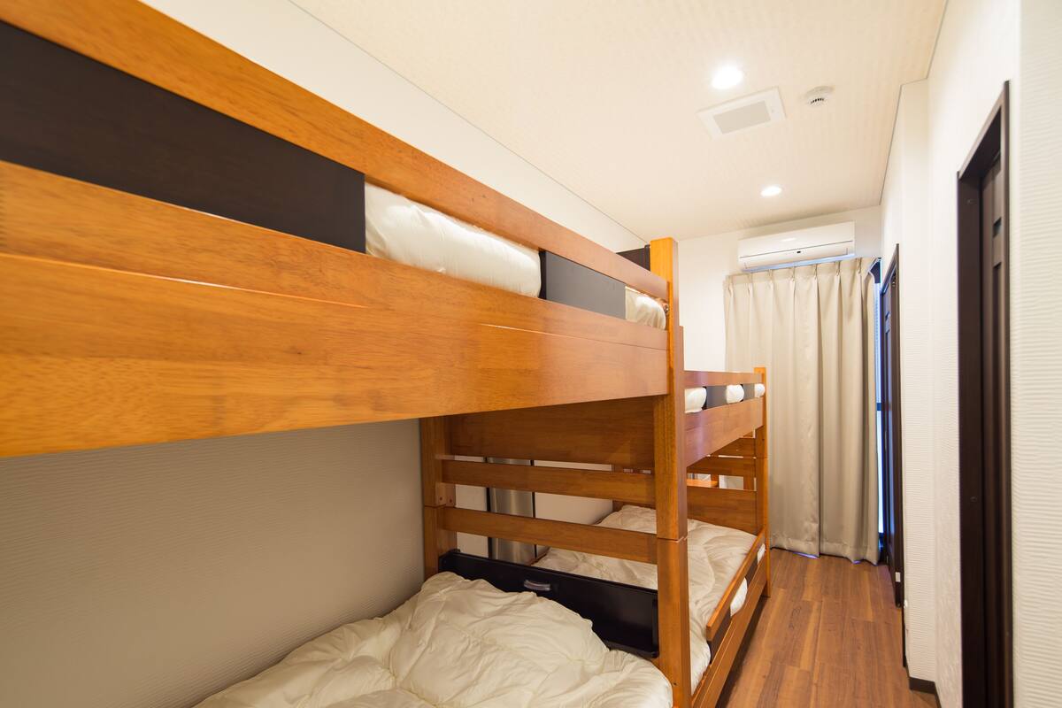 Una camera con un letto a castello, una testiera in legno, una scrivania e una finestra con tende.