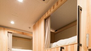 A room with bunk beds, wooden walls, and a carpeted floor.
