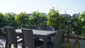 An outdoor patio with a table and chairs, surrounded by potted plants.
