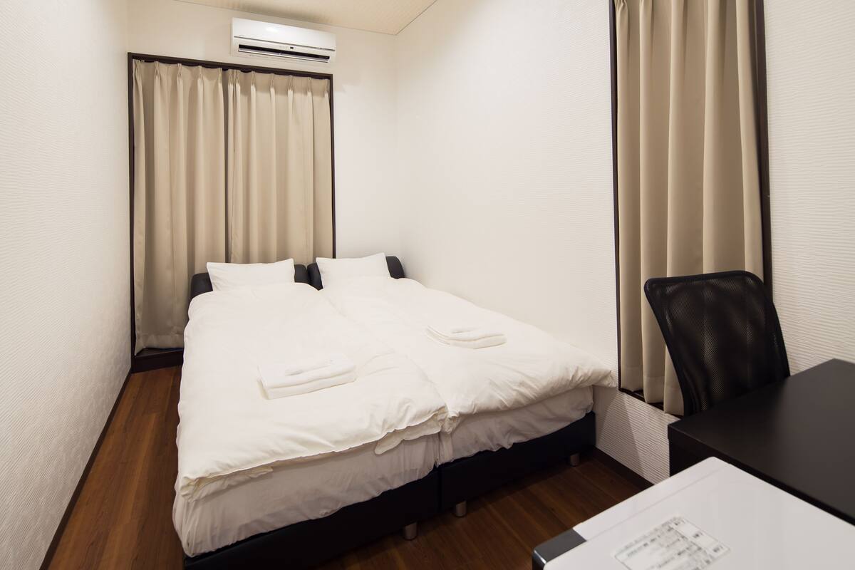 Una camera d'albergo con un letto, una scrivania e un condizionatore d'aria.