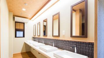 Un baño moderno con tres lavamanos, suelo de madera y un rebozo de azulejos.