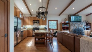 Une cuisine spacieuse avec des meubles en bois, un îlot central et une cheminée en pierre.