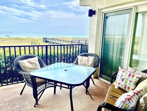 A balcony with a table and chairs, a view of the beach, and a sliding glass door. - 1st Floor Amelia South's Oceanfront Crown Jewel   (Fernandina Beach)