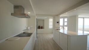 A modern kitchen with a central island, white cabinetry, and a view to the living area.