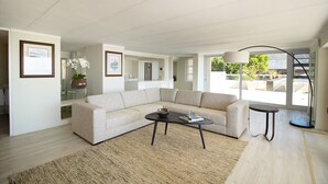 A spacious living room with a beige sectional sofa, a round coffee table, and a floor lamp.
