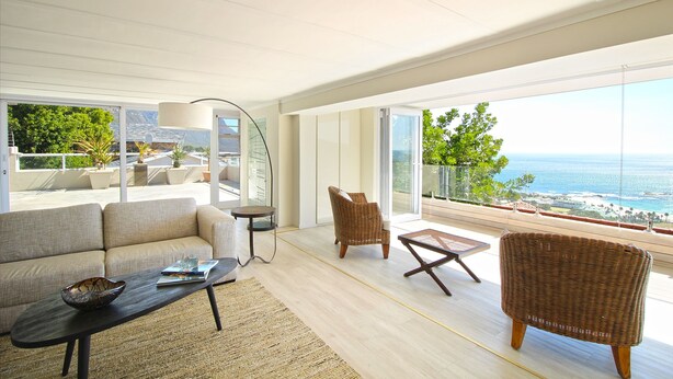 A modern living room with a sofa, a wicker chair, a coffee table, and a floor lamp.
