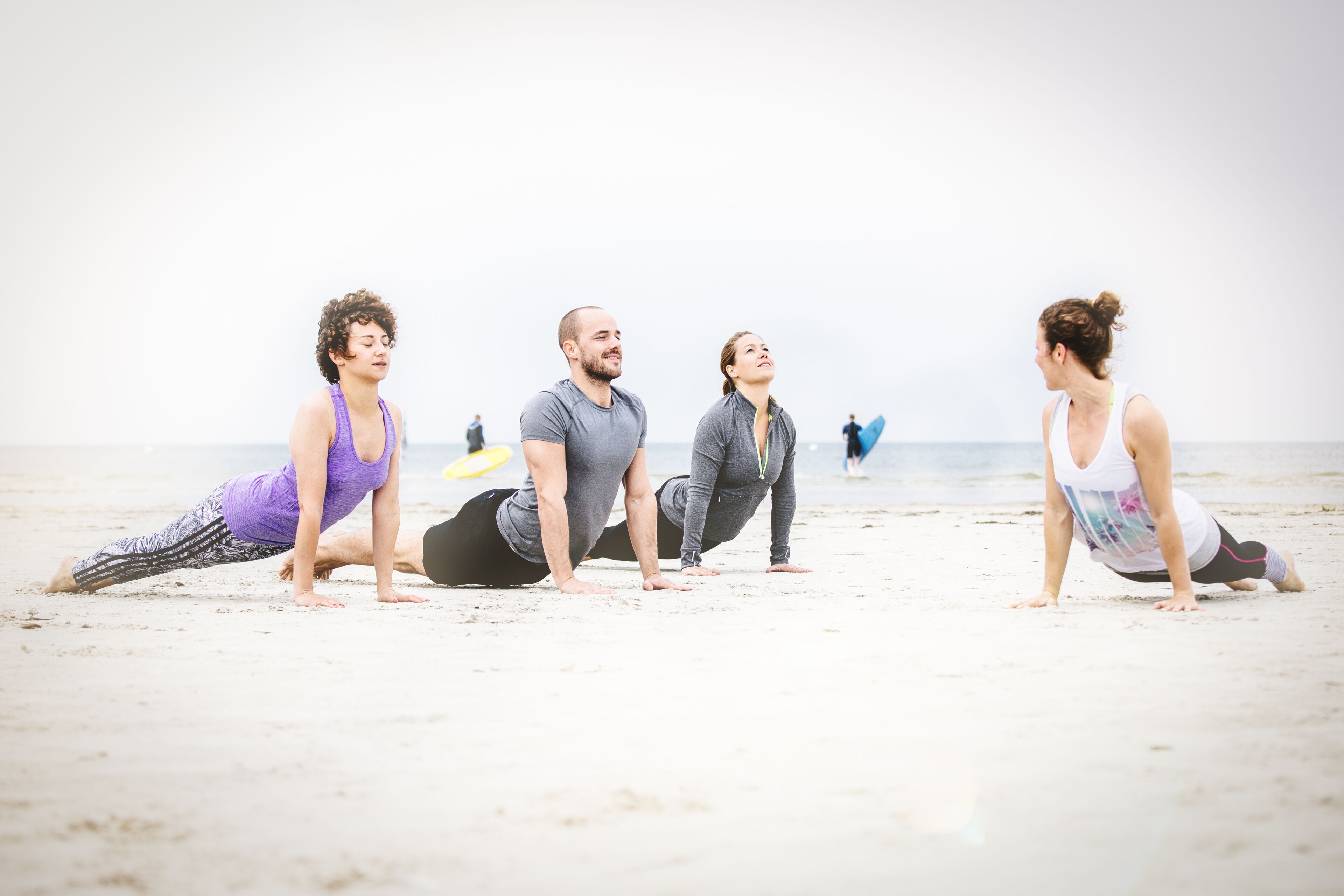 Four people doing a plank exercise on a beach.