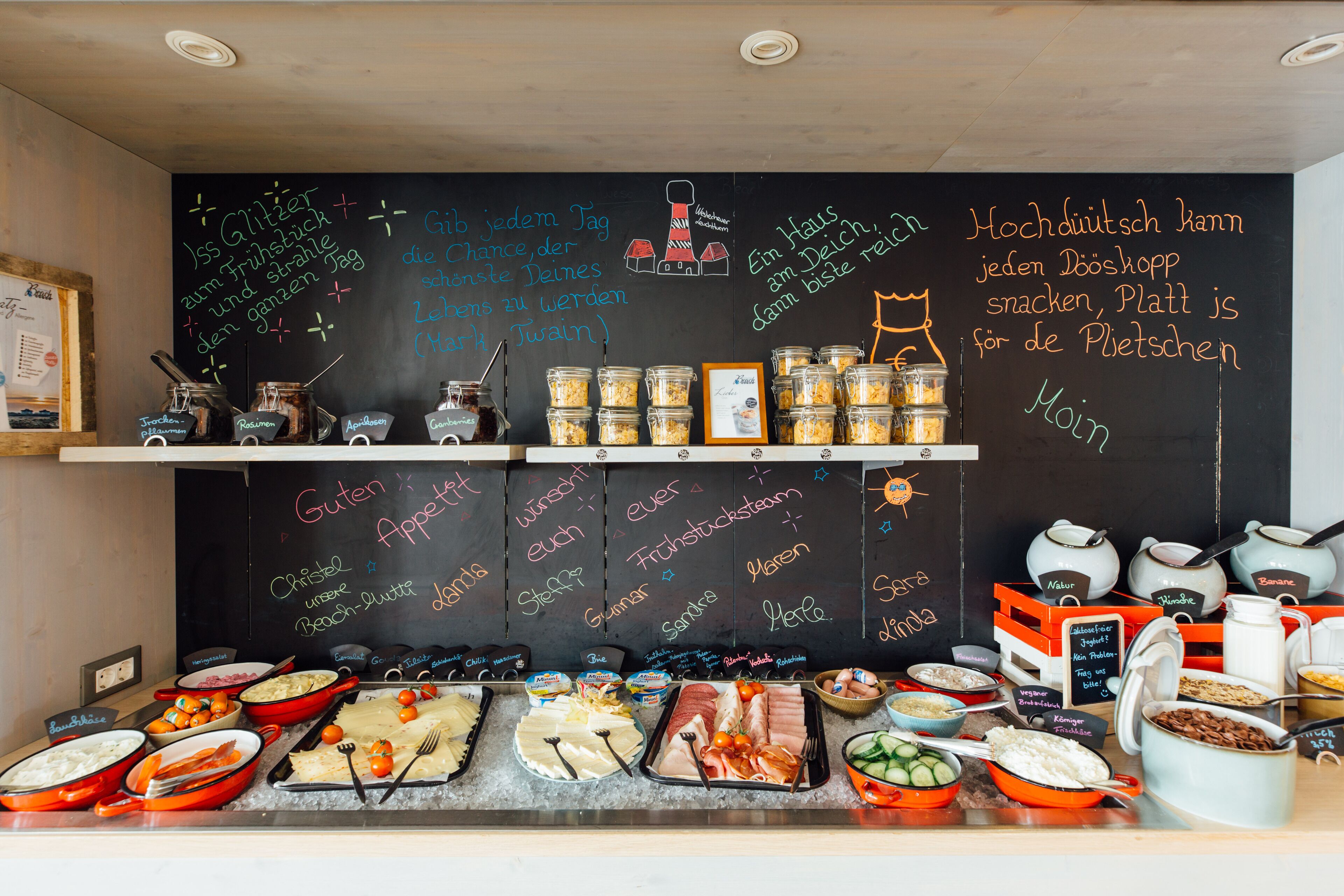 Een buffet met diverse gerechten en een krijtbordmenu in een restaurant.