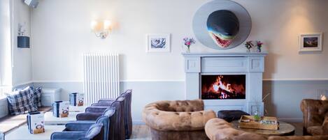 Una sala moderna con chimenea, zona de estar y un sombrero decorativo grande en la pared.