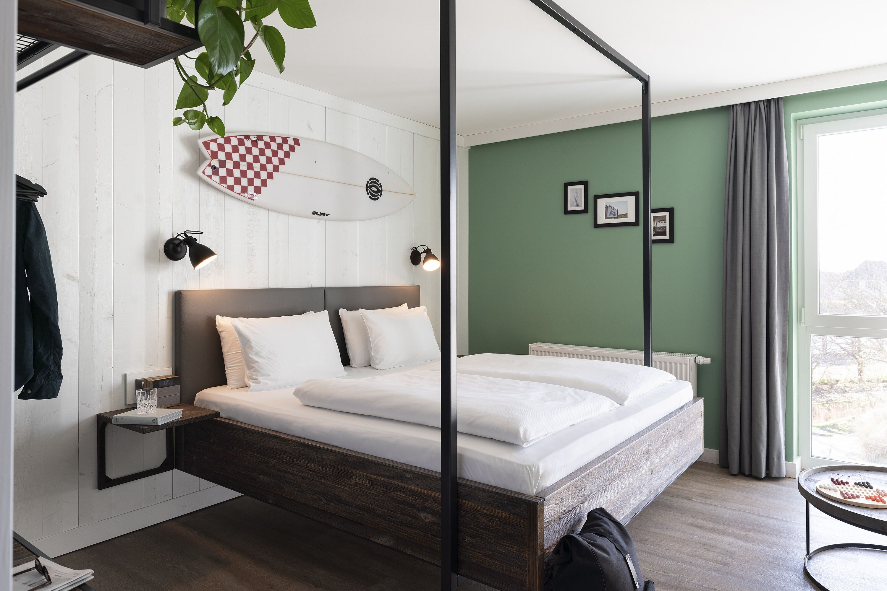 Un dormitorio moderno con cama, mesitas de noche, una decoración con una tabla de surf y una ventana con cortinas.