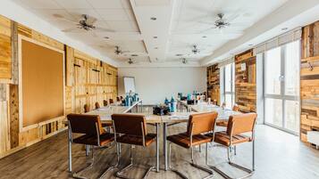 A conference room with a long table, four chairs, ceiling fans, and wooden panel walls.