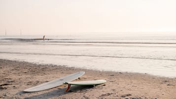 Dos tablas de surf sobre una playa arenosa con el océano al fondo.