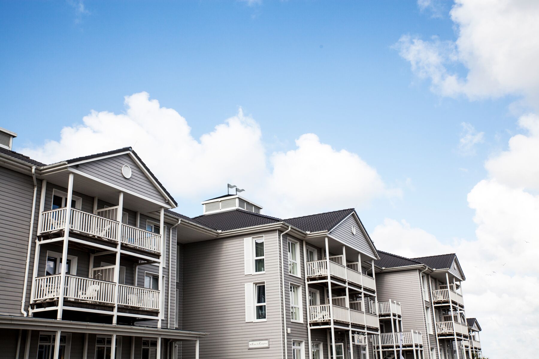 A row of multi-story residential buildings with balconies and a clear sky.