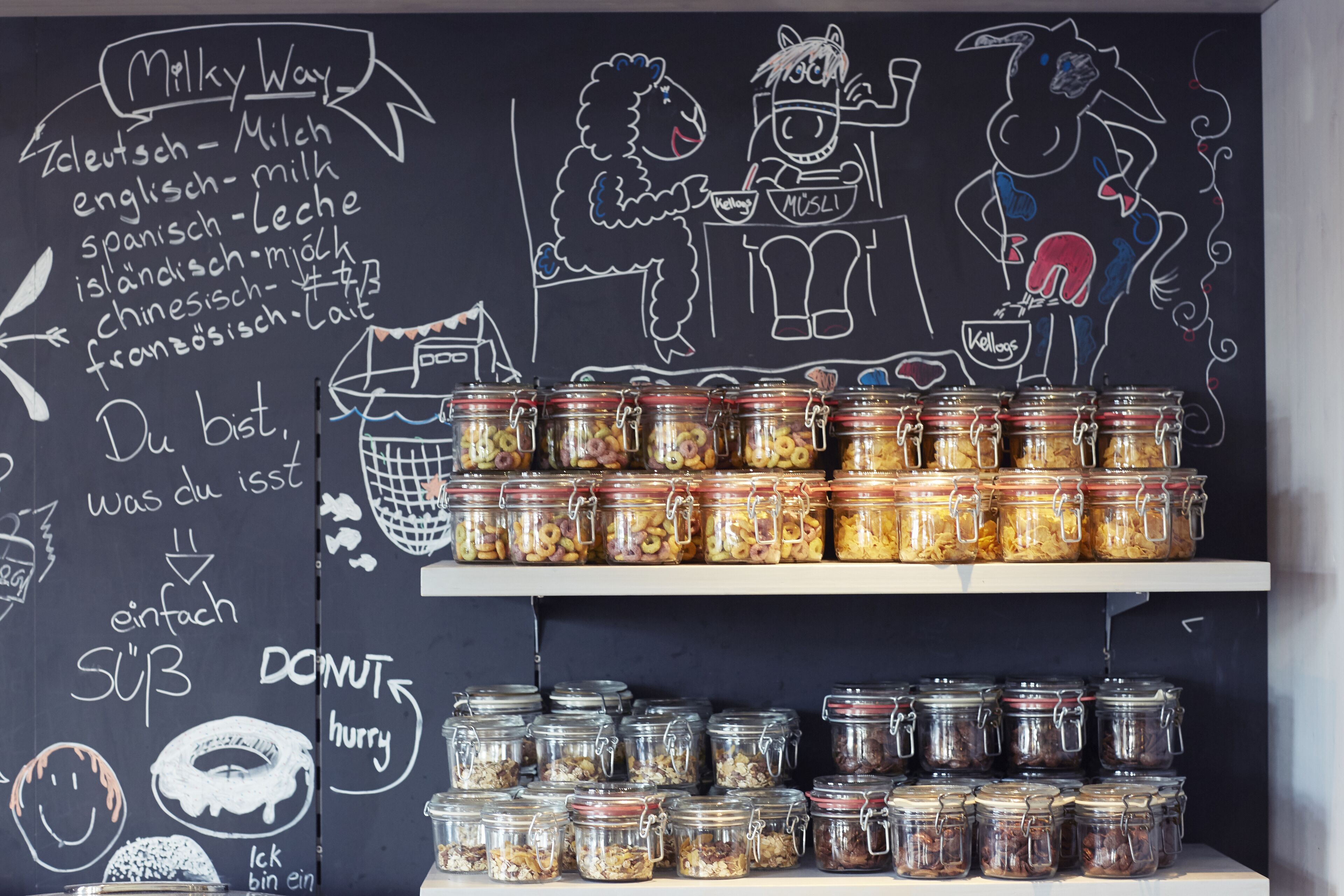 A chalkboard with food-related drawings and text, and shelves with jars of food items.