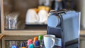 A coffee machine with a tray of colorful cups and a single white cup in front of it.