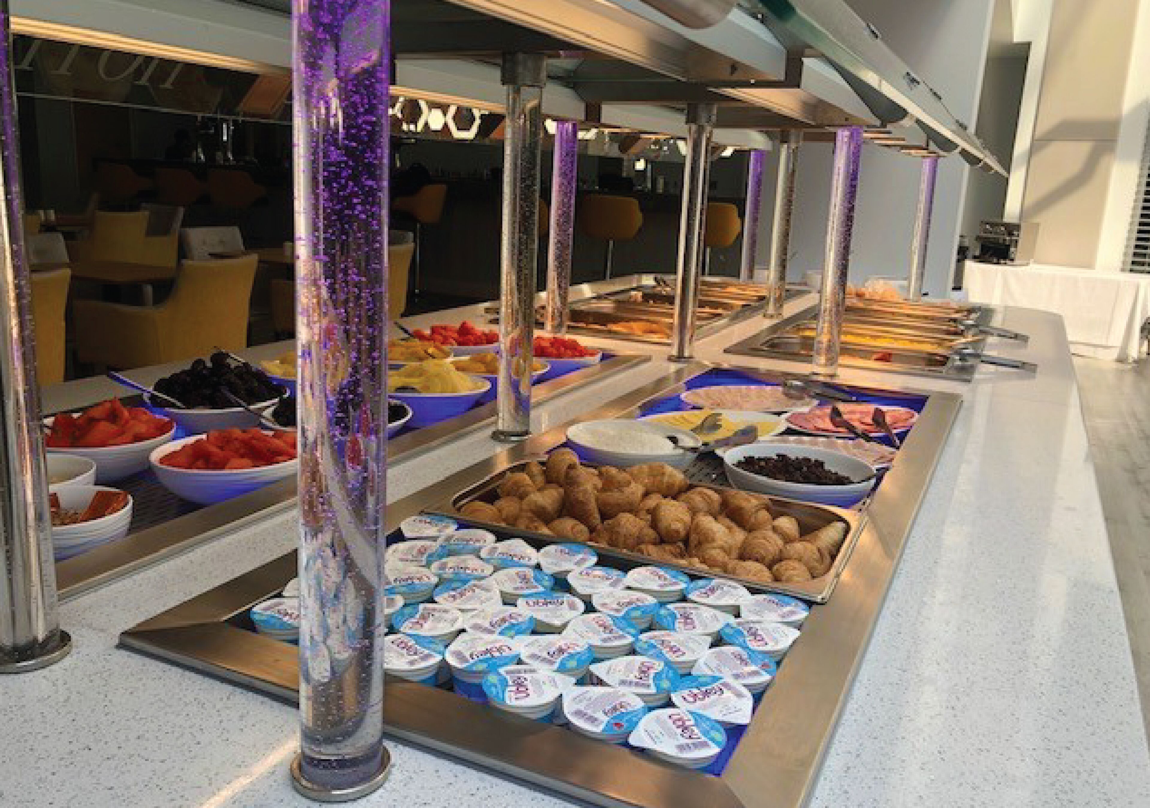 Un buffet proposant une variété de plats, notamment des fruits, des pâtisseries et des produits laitiers.