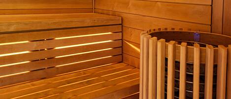 A sauna with wooden benches and a metal heating element.