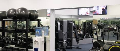 A gym with exercise equipment, water dispensers, and mirrors.
