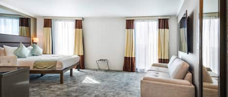 Una habitación de hotel con cama, sofá, escritorio y un espejo grande.