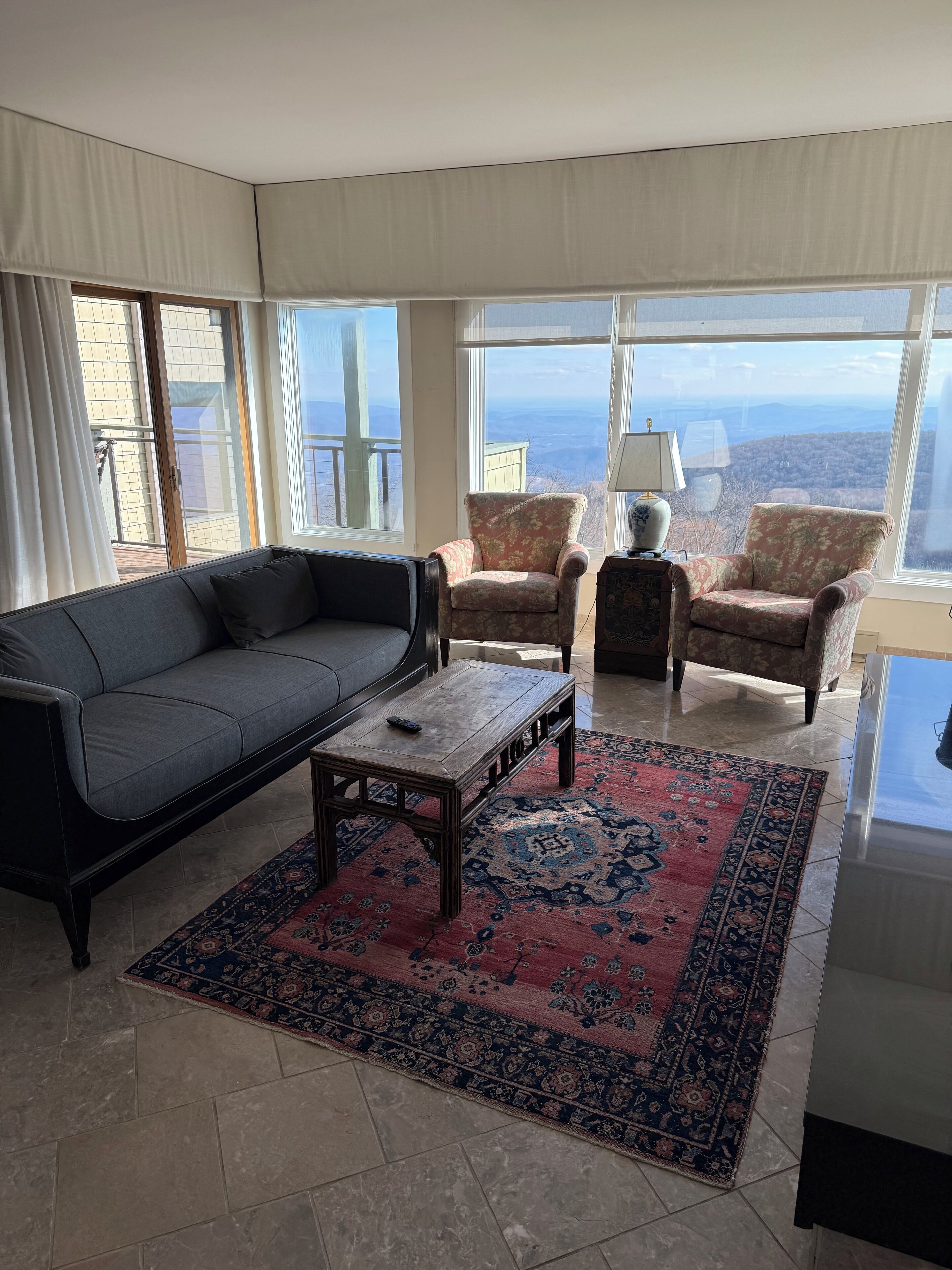 A living room with a sofa, armchairs, a coffee table, and a large window with a view.