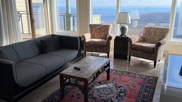 A living room with a sofa, armchairs, a coffee table, and a large window with a view.