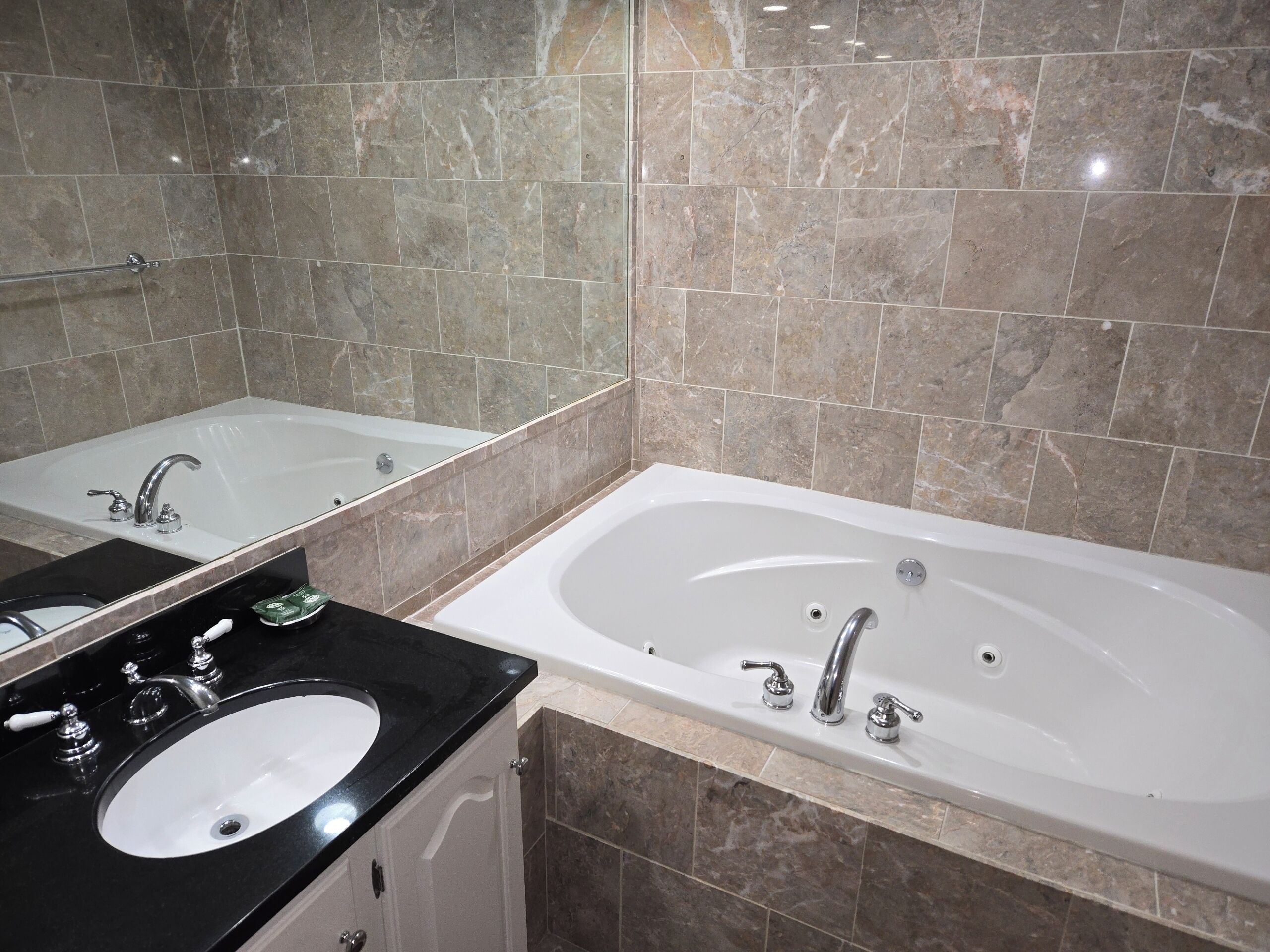 A modern bathroom with a large bathtub, a separate sink, and a mirror.