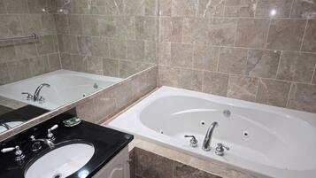 A modern bathroom with a large bathtub, a separate sink, and a mirror.