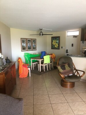 Un soggiorno con tavolo da pranzo, sedie, divano, un mobile in legno e una ventola a soffitto.