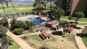 A pool area with lounge chairs, a barbecue area, and a picnic table.