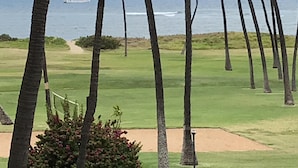 A golf course with a view of the ocean and a boat in the distance.