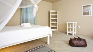 A bedroom with a bed, a nightstand, a wardrobe, a small table, and a suitcase.
