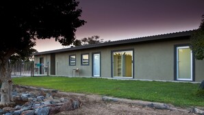 A modern building with a flat roof, large windows, and a grassy lawn.