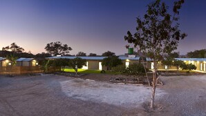 A row of single-story buildings with attached garages, surrounded by a gravel driveway and sparse landscaping.