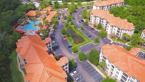 Vista aérea de una zona residencial con edificios de apartamentos, una piscina y una carretera.