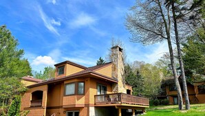 A two-story house with a stone chimney, wooden siding, and a balcony.