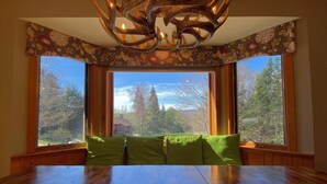A dining area with a large wooden table and green cushioned benches.