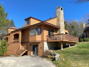 Ein zweistöckiges Haus mit einem Steinsschornstein, einem Balkon und einer überdachten Veranda.