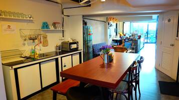 A compact kitchen with a wooden table, a bench, and a refrigerator.