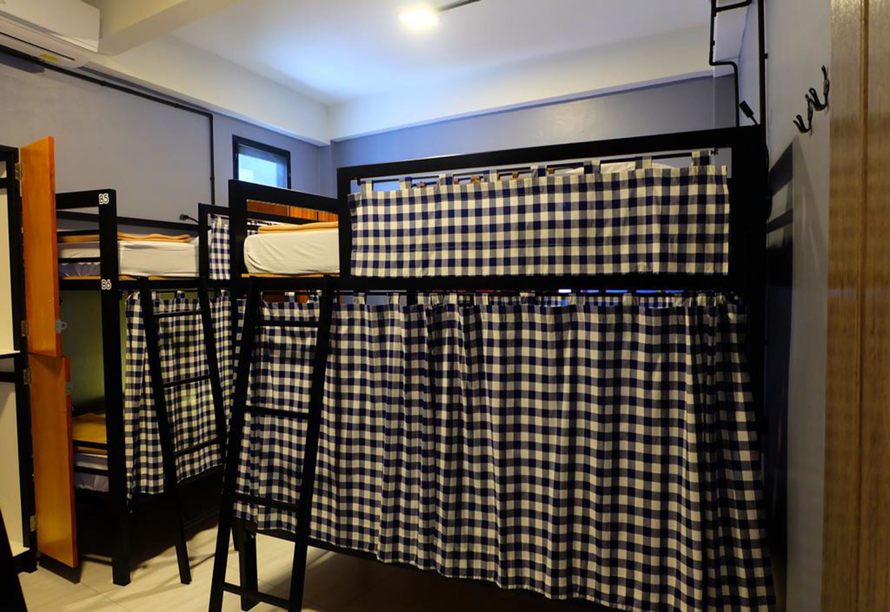 A dormitory room with bunk beds, a wooden ladder, and a window.