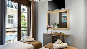 A hotel room with two beds, a TV, a mirror, and a desk with a chair. - City Breeze Apartment (Chania)