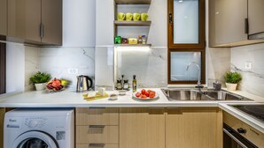 A modern kitchen with a built-in washer, a sink, and a window above the countertop. - City Breeze Apartment (Chania)