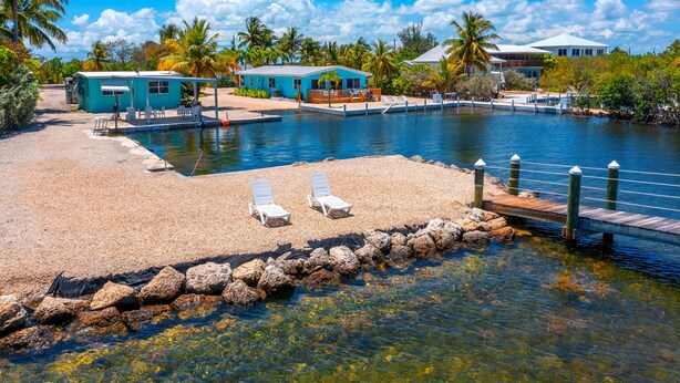 Un complexe hôtelier situé en bord de mer, doté d’une piscine, de chaises longues et d’un quai.