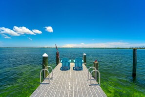 A pier with two blue Adirondack chairs facing a calm body of water under a clear blue sky. - Waterfront Cozy Cottage with Boat Ramp & Dock (Little Torch Key)