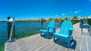 Une jetée avec deux chaises Adirondack bleues et une rambarde en métal.