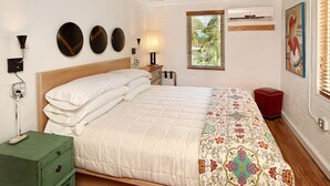 A bedroom with a wooden bed, a ceiling fan, a window with blinds, a green nightstand, and a red chair. - Folly Vacation 114B Townhouse, perfect family vacation, pets welcome! (Folly Beach)