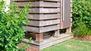 A wooden structure with a slatted design, possibly a shed or storage unit, surrounded by a well-maintained lawn and dense foliage. - Folly Vacation 114B Townhouse, perfect family vacation, pets welcome! (Folly Beach)